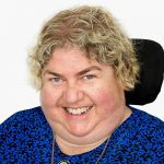 QDN board member Sharon Boyce, she has short blonde hair and is wearing a blue top. She is smiling at the camera.