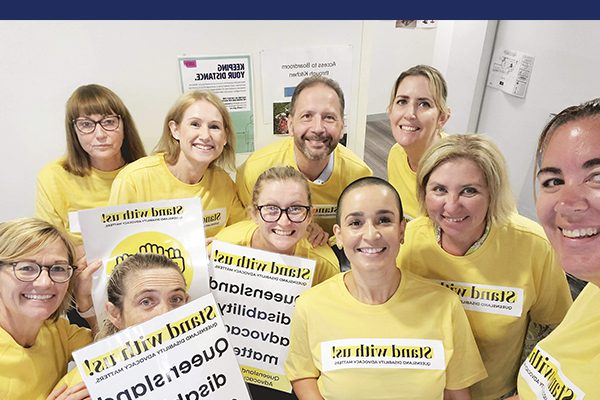 A group of men and women in yellow Stand with us Campaign shirts taking a group selfie.