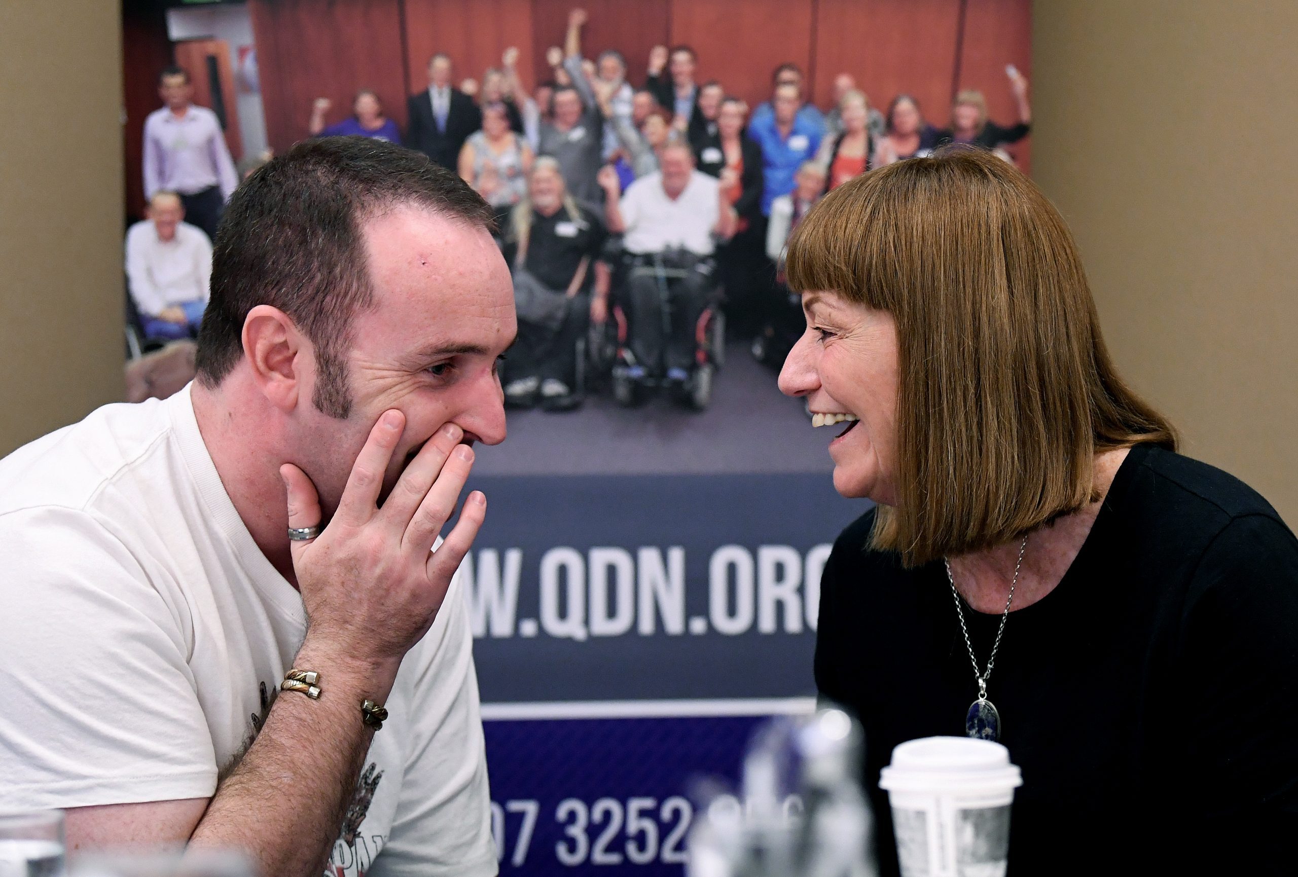 A man and a women sitting down and talking to each other and smiling.