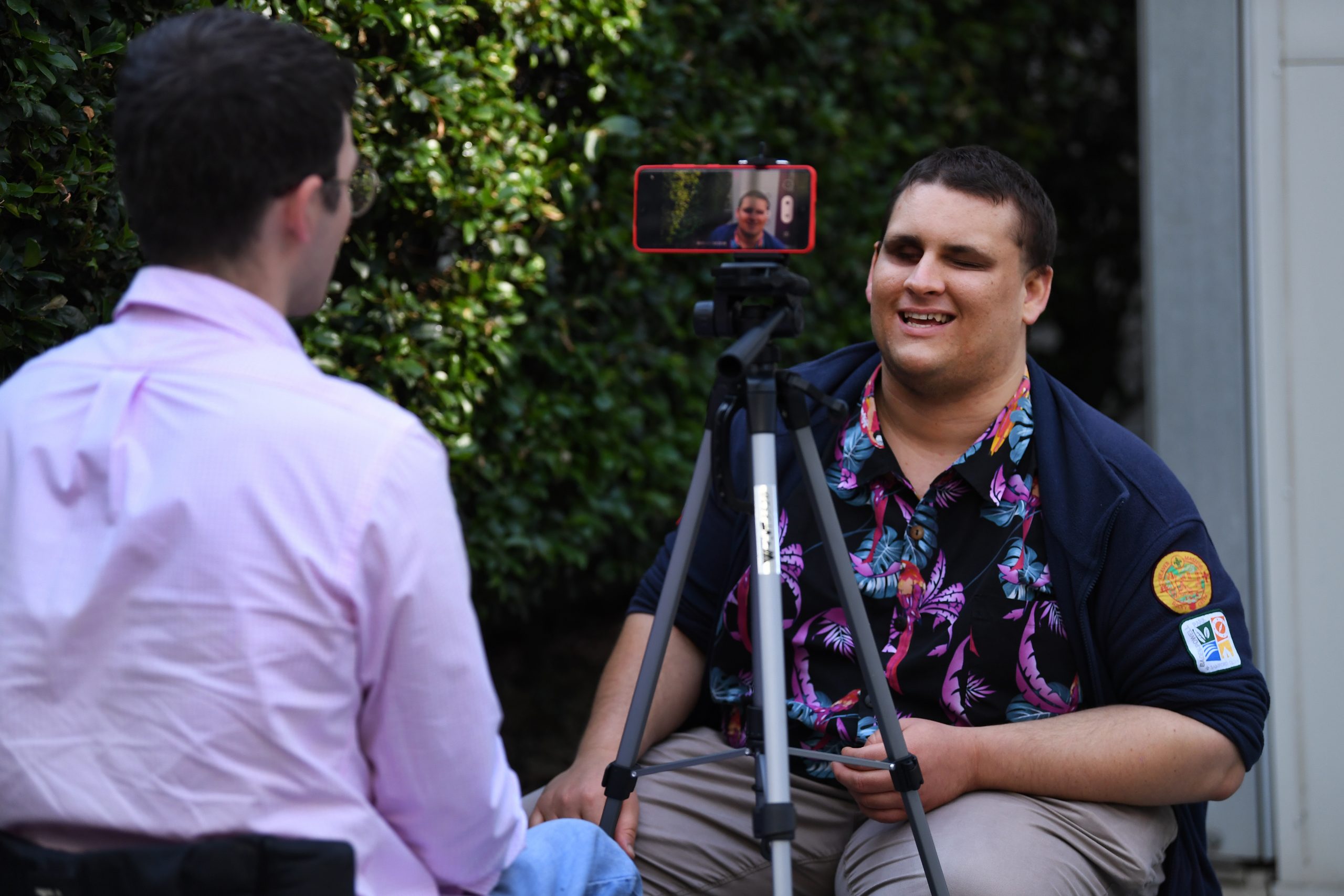 A man being interviewed and recorded on an iphone which is set up on a tripod.