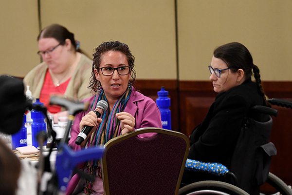 At a table with 3 people, one woman is speaking with a microphone.