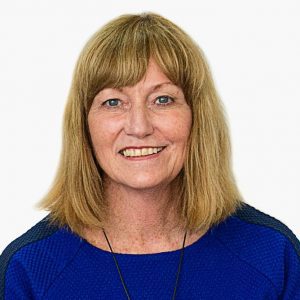 Photo of a woman with shoulder length light brown hair, wearing a deep blue shirt is smiling towards the camera.