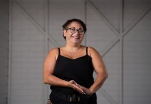 Lady with a black sleeveless top on laughing as she looks to the side.