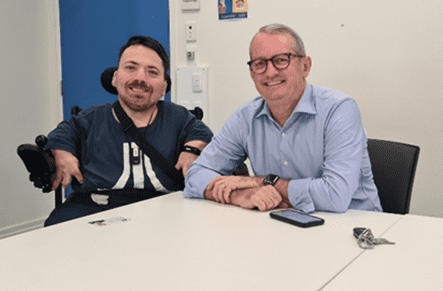 Picture of two males sat at a table at a Peer Support meeting, both smiling