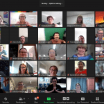 A screenshot of 25 men and women in different locations on a Zoom meeting. They are all looking at the screen smiling.