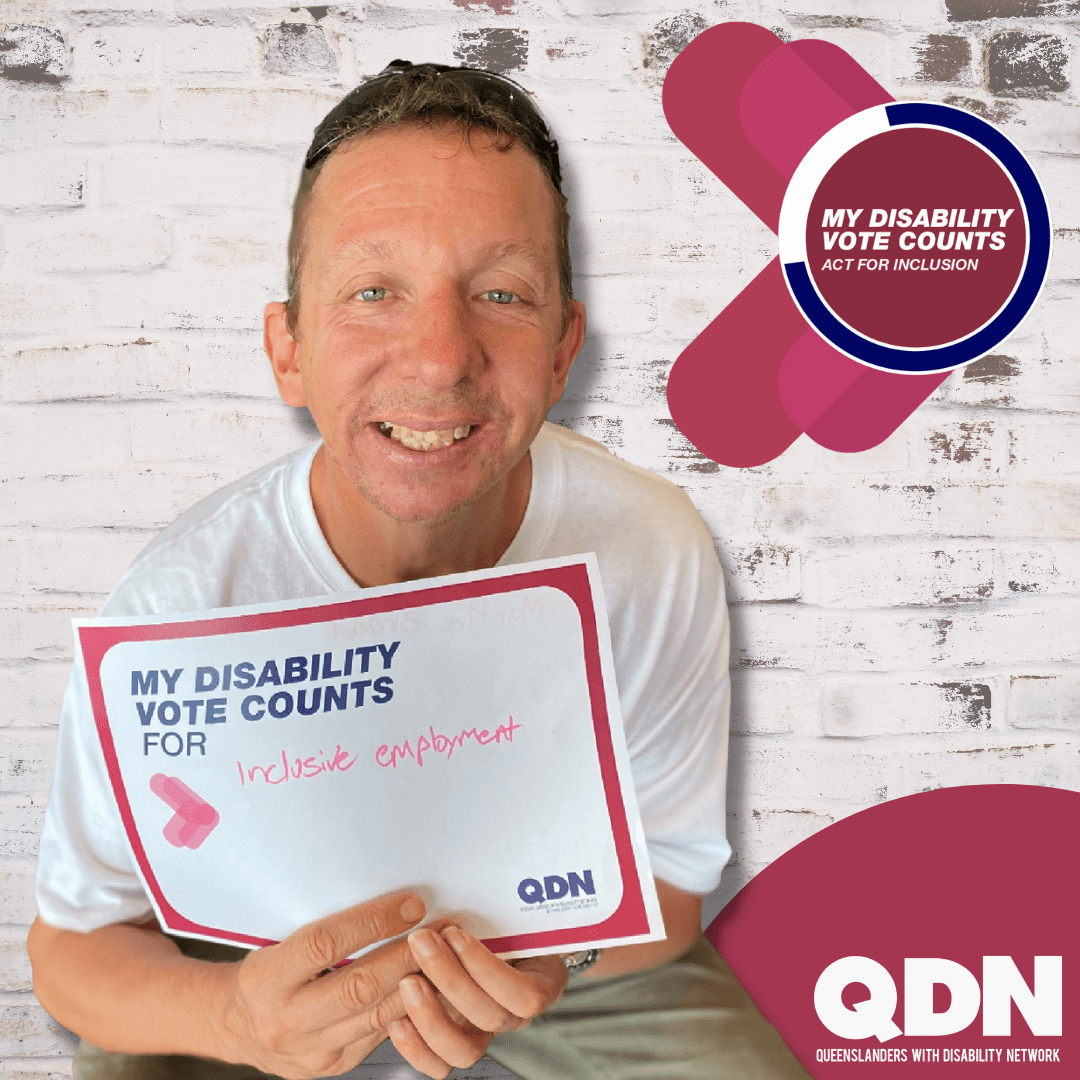 A man wearing a white shirt holding a sign that says My disability vote counts for and written in pen "Inclusive employment". Then it says My disability vote counts, Act for inclusion. QDN Queenslanders with Disability Network.