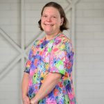 Woman with a flower dress posing for a camera. 