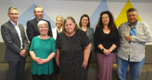 This image depicts eight individuals posing for a group photo, all facing the camera. These individuals constitute the Council for the National Centre of Excellence in Intellectual Disability Health. Among them is Donna Best, a member of QDN (Queenslanders with Disability Network).