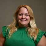 Woman with shoulder length blonde hair and wearing a green dress