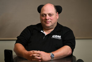 Man with a black QDN shirt on and sitting in a wheelchair.