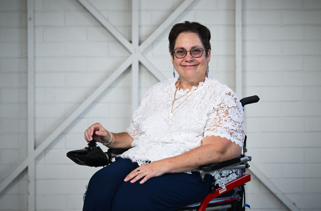 A woman sitting on her wheelchair smiling at the camera