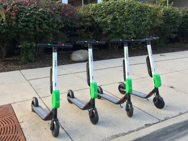 A row of Lime scooters on a kerbside