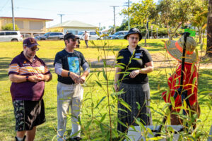 Four people looking at plants in a park.