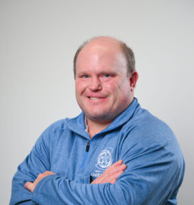 A man in a blue shirt with his arms folded in front