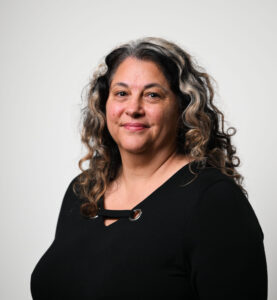 Woman wearing a black shirt looking at the camera, she has long hair.