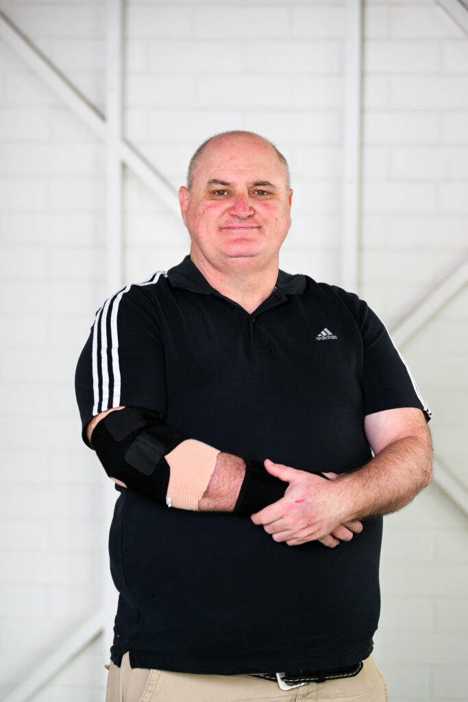 Man in a black shirt with an elbow brace.