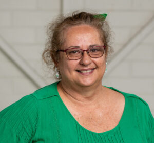 A woman in a green shirt smiling at the camera
