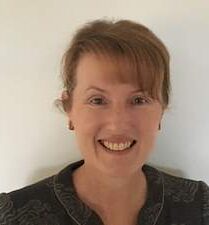 A woman in a black top with short red hair smiling at the camera