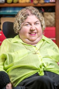 A woman with blonde hair wearing a green shirt smiling at the camera