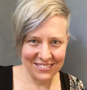 Woman with short blonde hair smiling at the camera