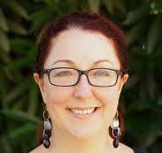 A woman with glasses smiling at the camera