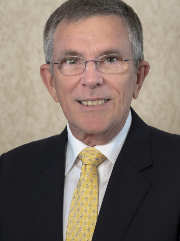 Man wearing a suite and glasses with a yellow tie.