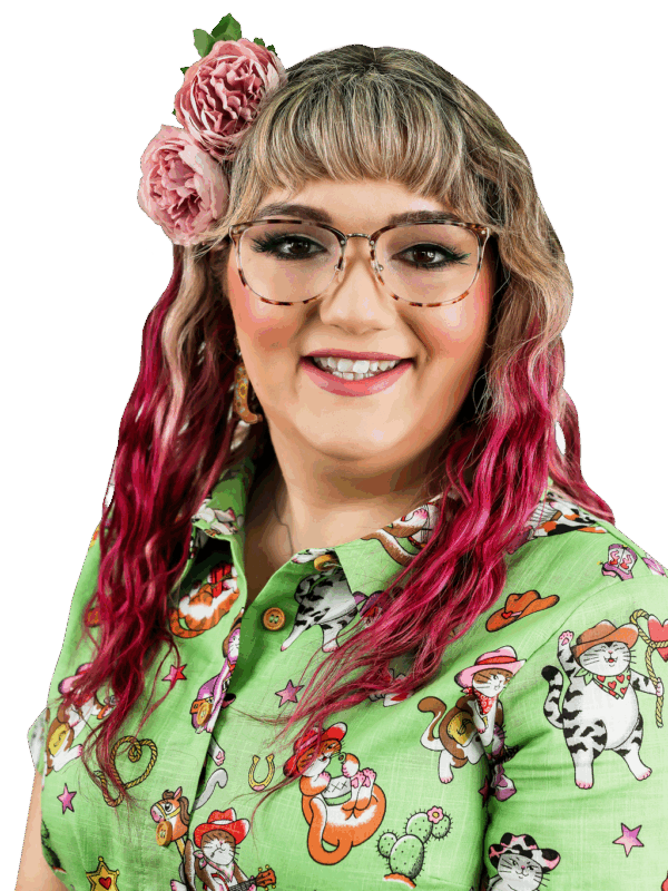 A person with purple hair and a green dress with cowboy cats is smiling
