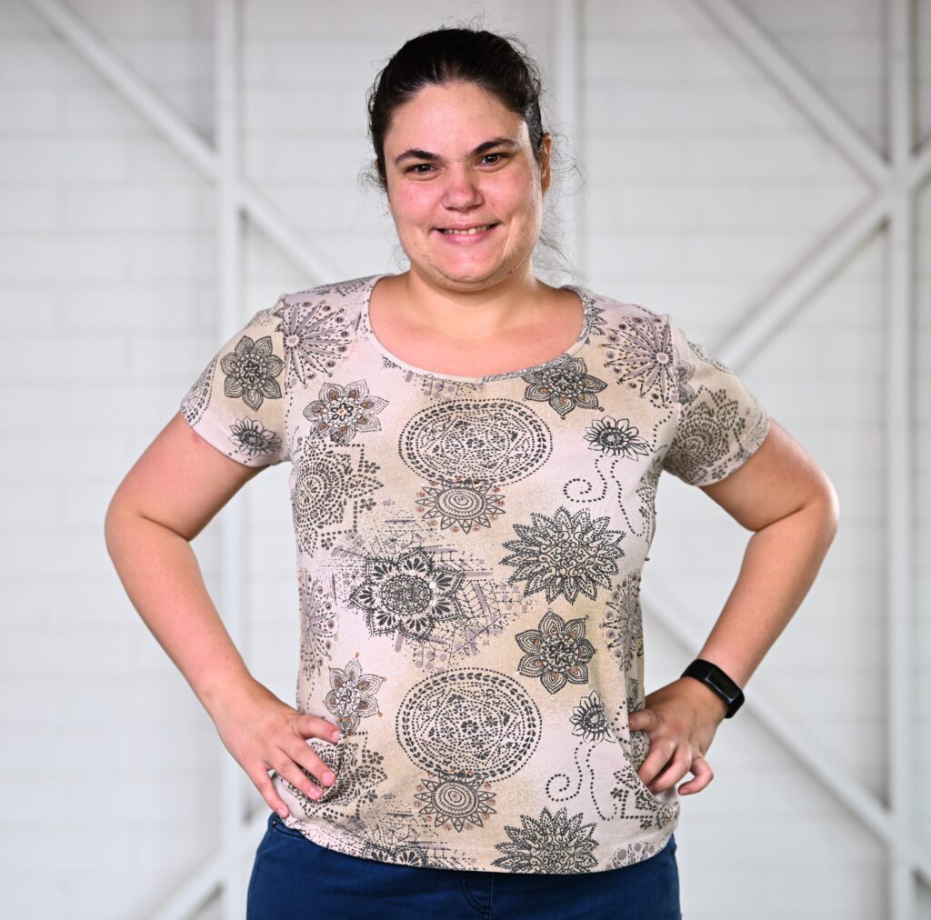 A woman standing in front of a white wall with her hands on her hips.