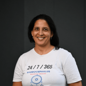 Woman with dark hair , wearing a white shirt smiling.